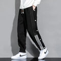 Men's black loose-fit sweatpants with ankle ties and a drawstring high waist on a neutral background.