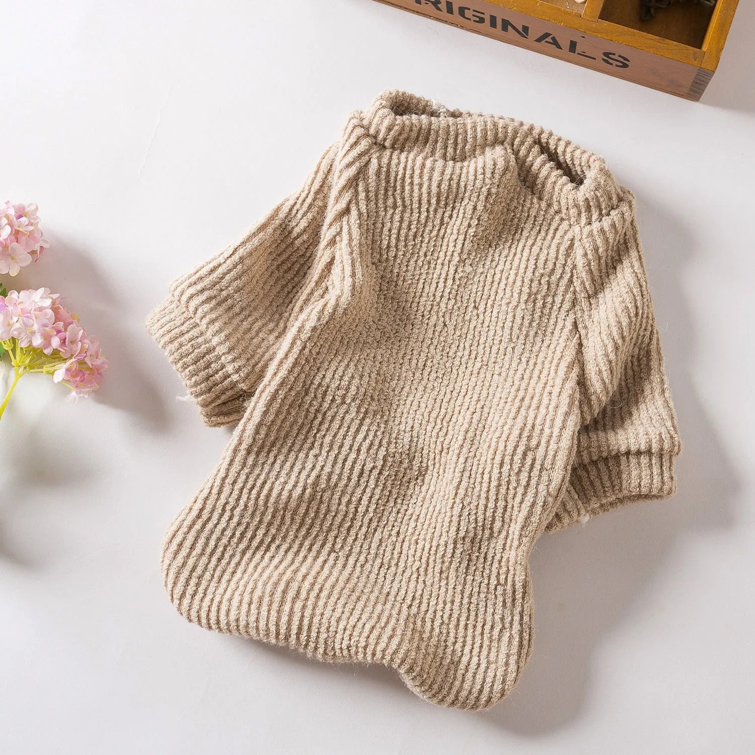 Brown knitted pullover sweater on a small dog, showing four-leg design for full coverage.