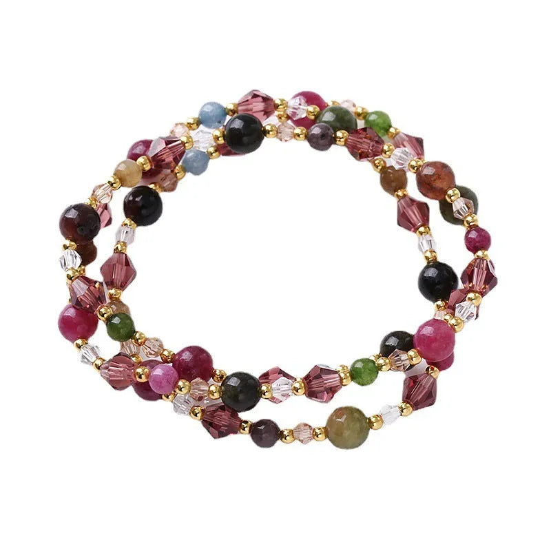 Close-up of a women's hand-made three-ring crystal bracelet with colourful beads on an adjustable rope.