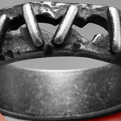 Close-up of a stainless steel double ring with punk stitching style detail on a dark background.