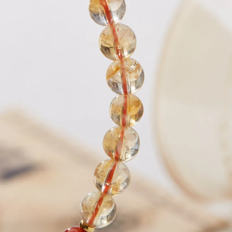 Close-up of a hand-woven citrine five sutra bracelet with 6mm geometric beads on a wrist.