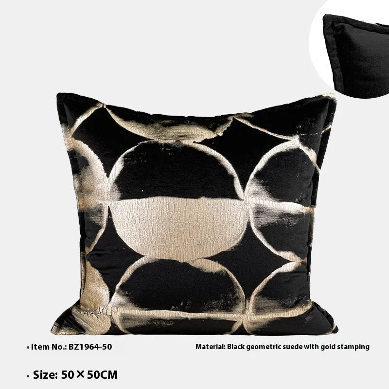 Black and gold abstract pattern decorative cushion with removable cover on a grey sofa.