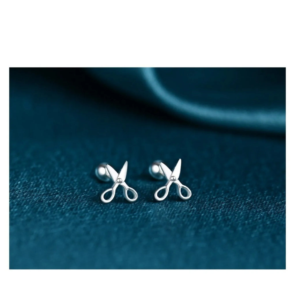Silver screw-back ear nail with a small scissor charm for cartilage piercing.