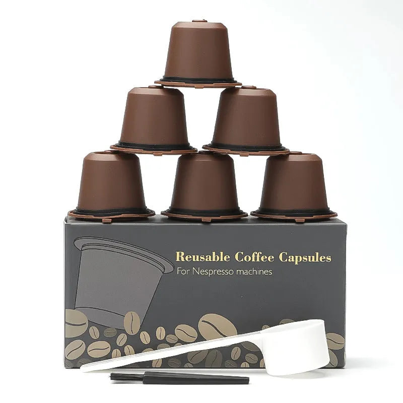 Six reusable black plastic coffee capsule filter cups with a spoon on a table