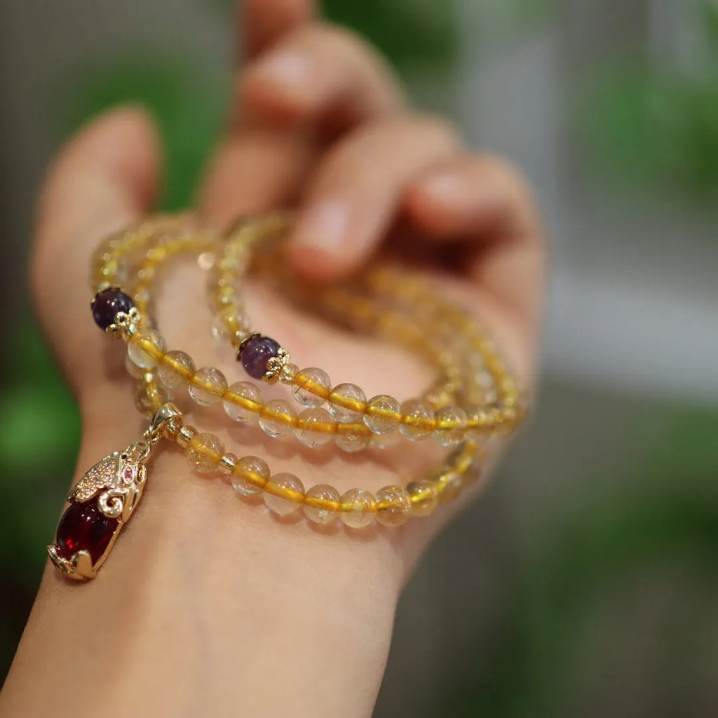 Natural quartz bracelet with three gold-coloured rings and hanging chopstick charms in a Chinese style.