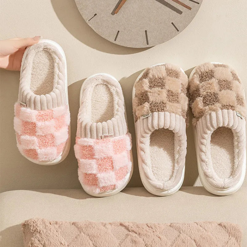 Women's plaid patterned coral velvet indoor slippers with a thick soft sole on a wooden floor.