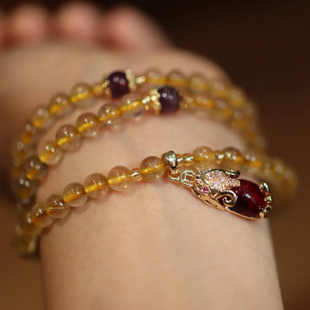 Natural quartz bracelet with three gold-coloured rings and hanging chopstick charms in a Chinese style.
