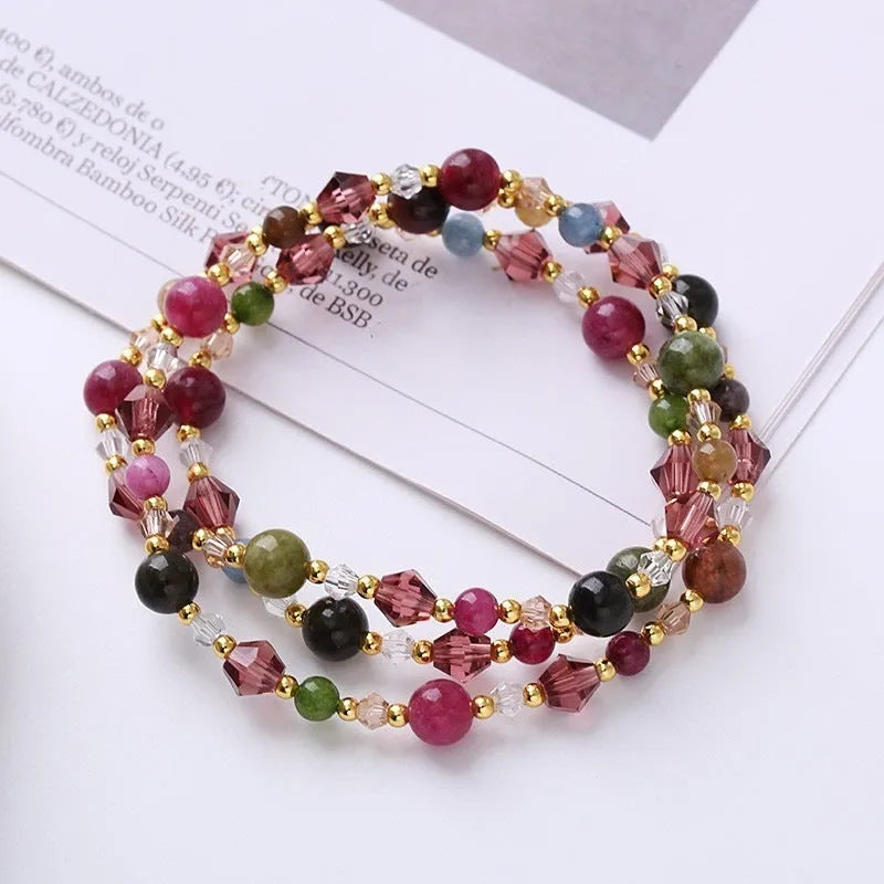 Close-up of a women's hand-made three-ring crystal bracelet with colourful beads on an adjustable rope.