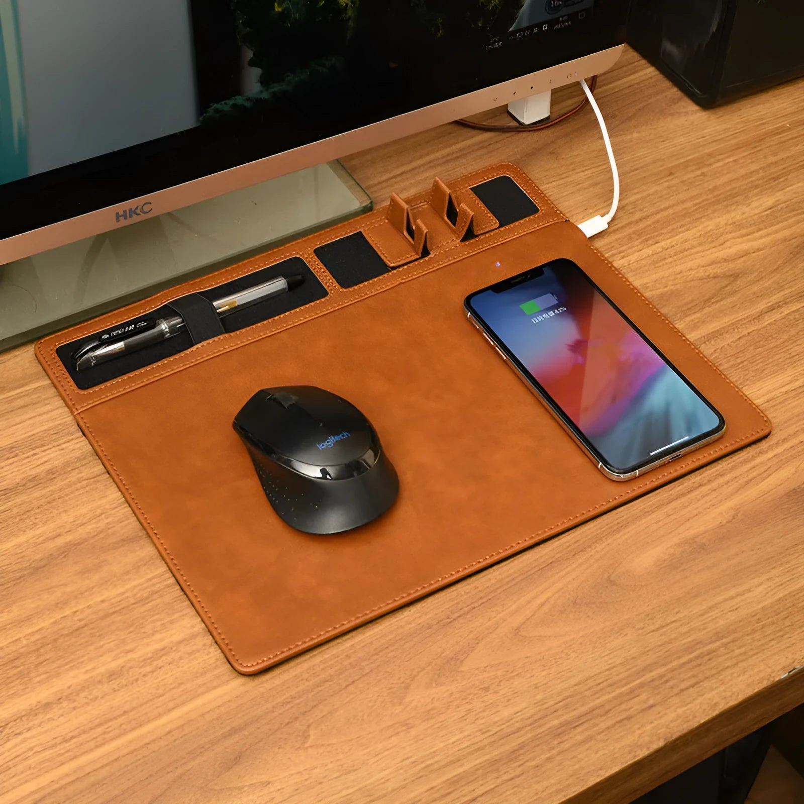 Large pink wireless charging mouse pad with integrated mobile phone holder on a desk.