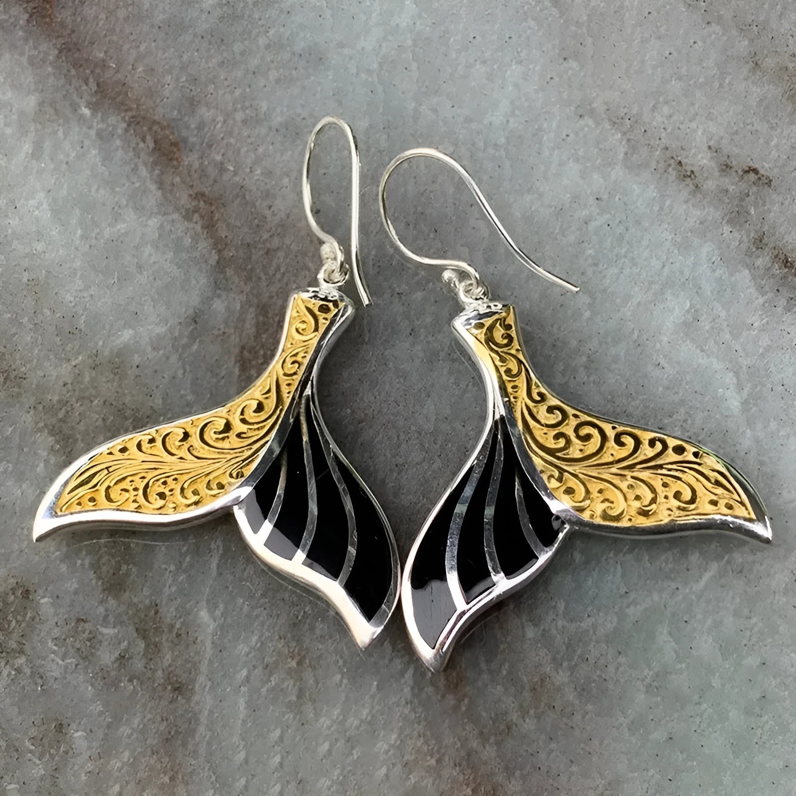 A pair of gold-coloured alloy fishtail earrings with a detailed whale tail design on post studs.