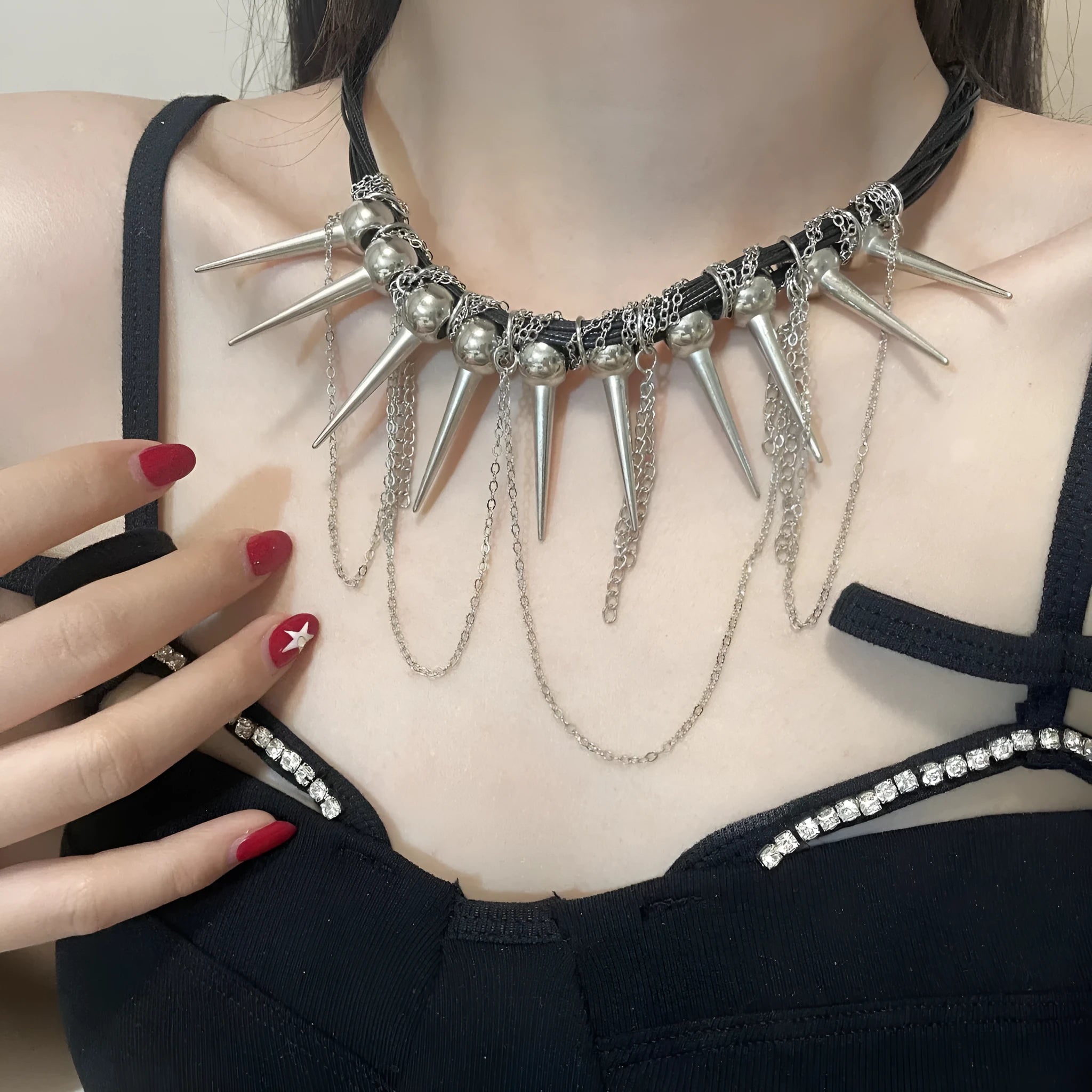Close-up of a leather necklace with round beads, a winding tassel, and silver rivet details on a dark background.