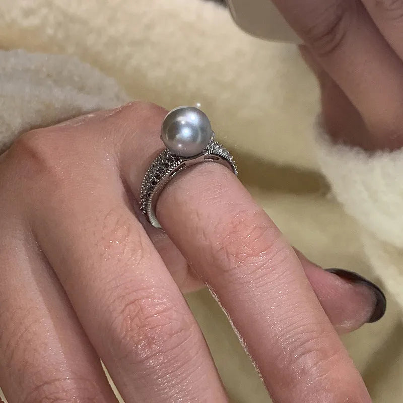 Adjustable open geometric copper ring with a black pearl for women on an index finger.