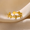 Geometric women's ring in titanium steel with a gold diamond finish on a plain background.