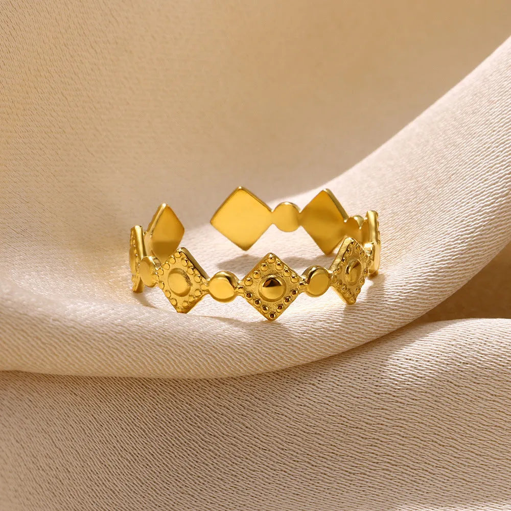Geometric women's ring in titanium steel with a gold diamond finish on a plain background.