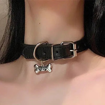 Black leather pet collar with small bell, showing adjustable buckle and cute cat paw design.