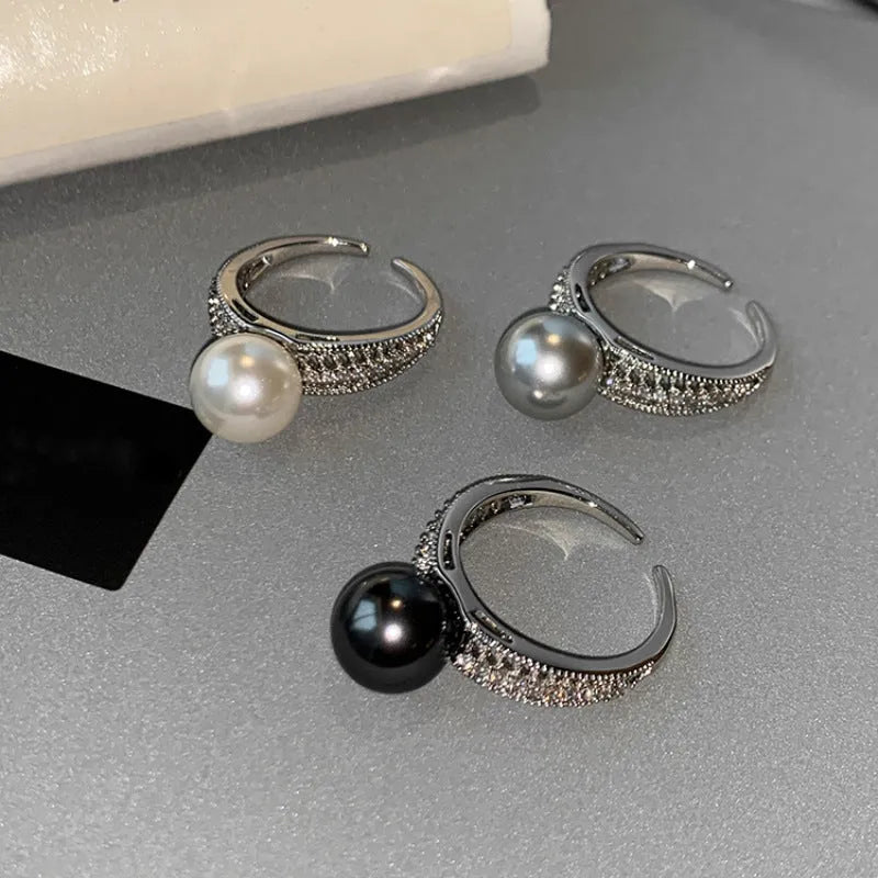 Adjustable open geometric copper ring with a black pearl for women on an index finger.