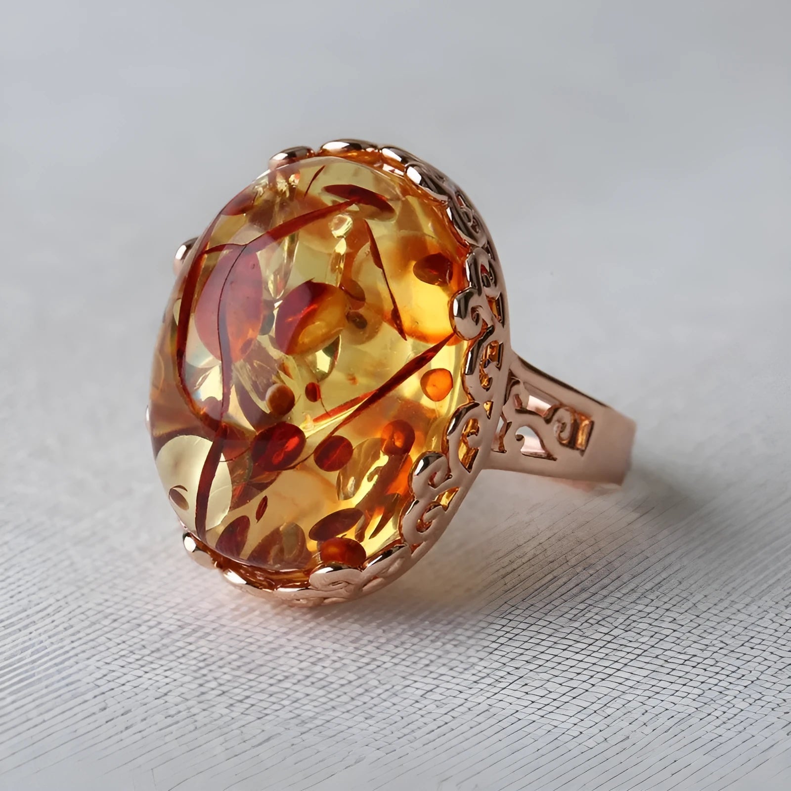 Beeswax ethnic style amber ring with gold-tone alloy band on a wooden surface.