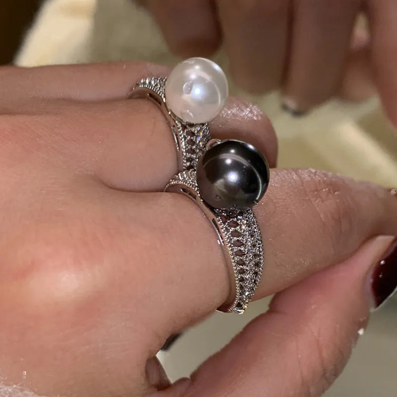 Adjustable open geometric copper ring with a black pearl for women on an index finger.