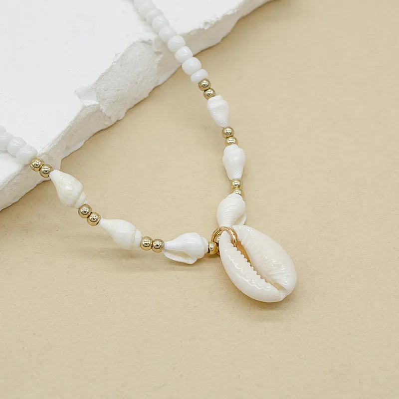 Close-up of a white conch shell bead necklace for women, showing the mother pearl shellfish pendant on a regular chain.