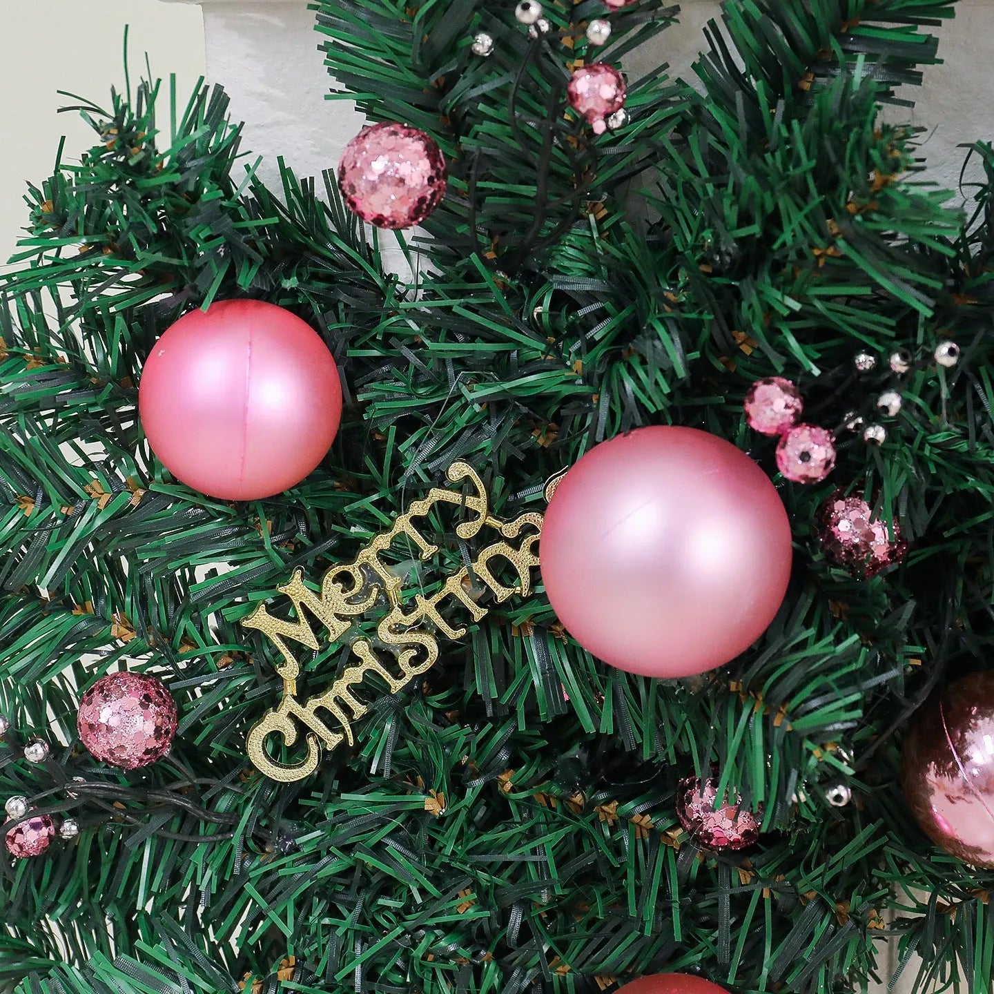 Pink artificial Christmas rattan vine garland with fairy lights draped on a mantelpiece