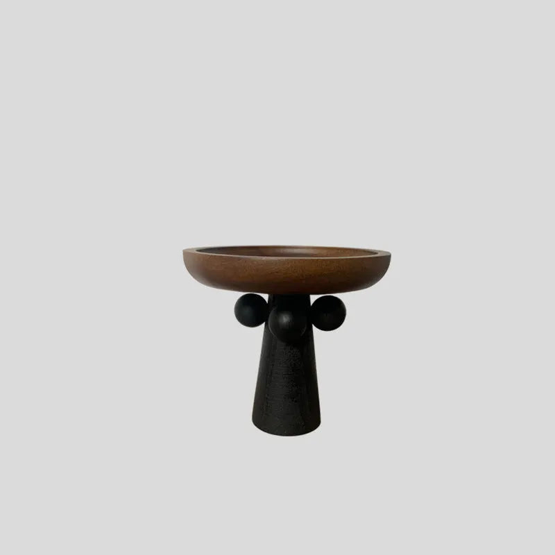 Round wooden tray with high Nordic-style legs in a light wood finish holding a candle