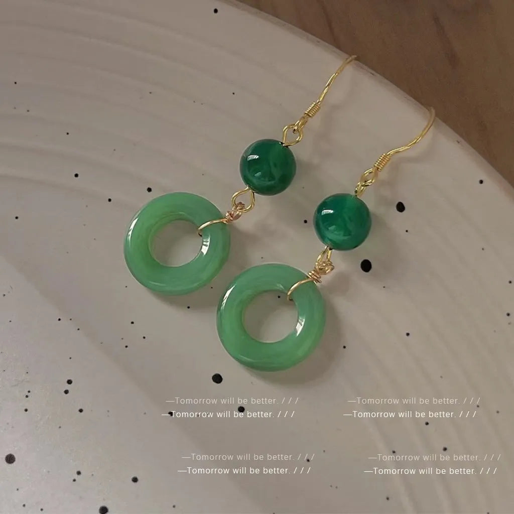 A pair of green and gold geometric earrings with a Chinese peace buckle and ring design.