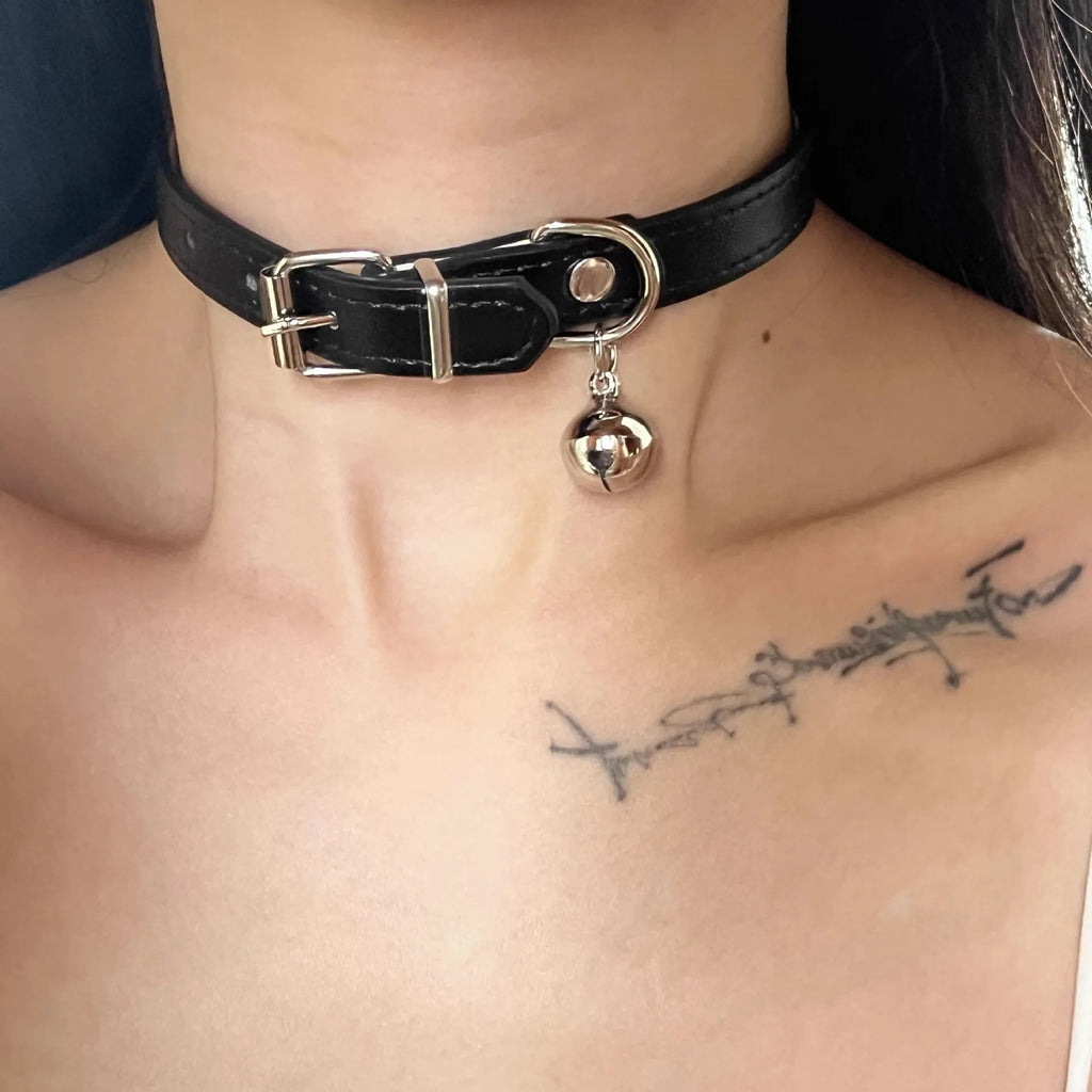 Black leather pet collar with small bell, showing adjustable buckle and cute cat paw design.