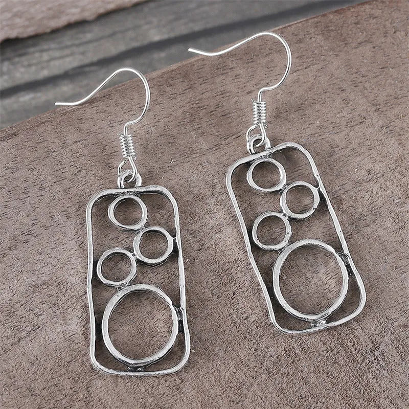 A pair of antique silver round ring earrings with a geometric irregular square design.