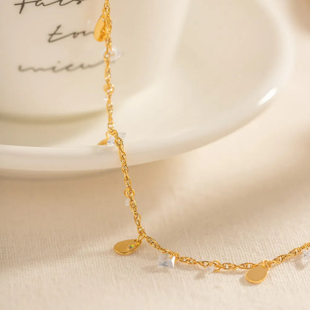 Silver stainless steel women's anklet with geometric and water drop tassel charms.