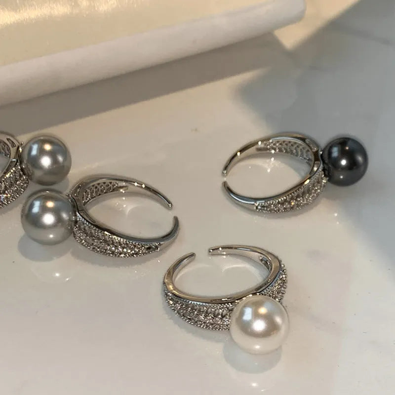 Adjustable open geometric copper ring with a black pearl for women on an index finger.