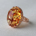 Beeswax ethnic style amber ring with gold-tone alloy band on a wooden surface.