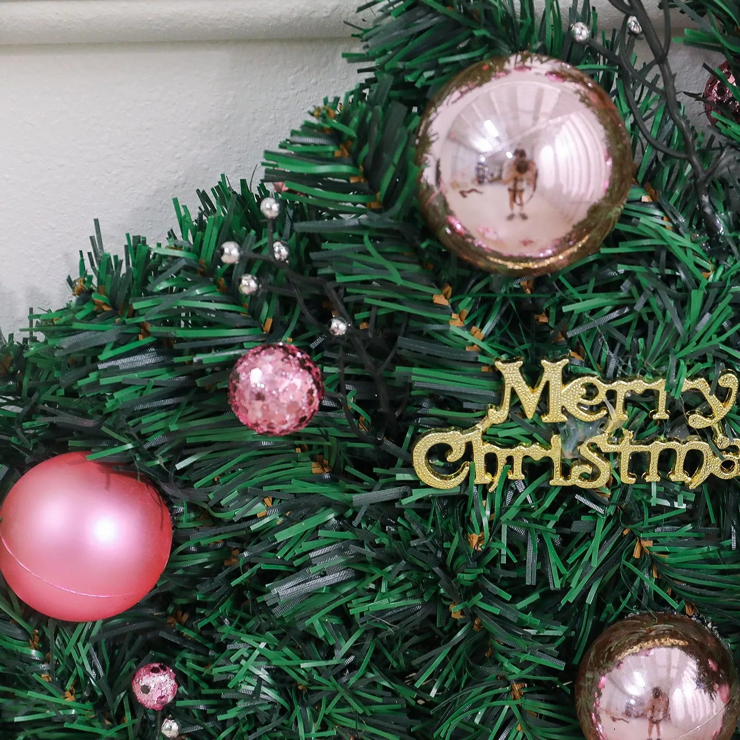 Pink artificial Christmas rattan vine garland with fairy lights draped on a mantelpiece
