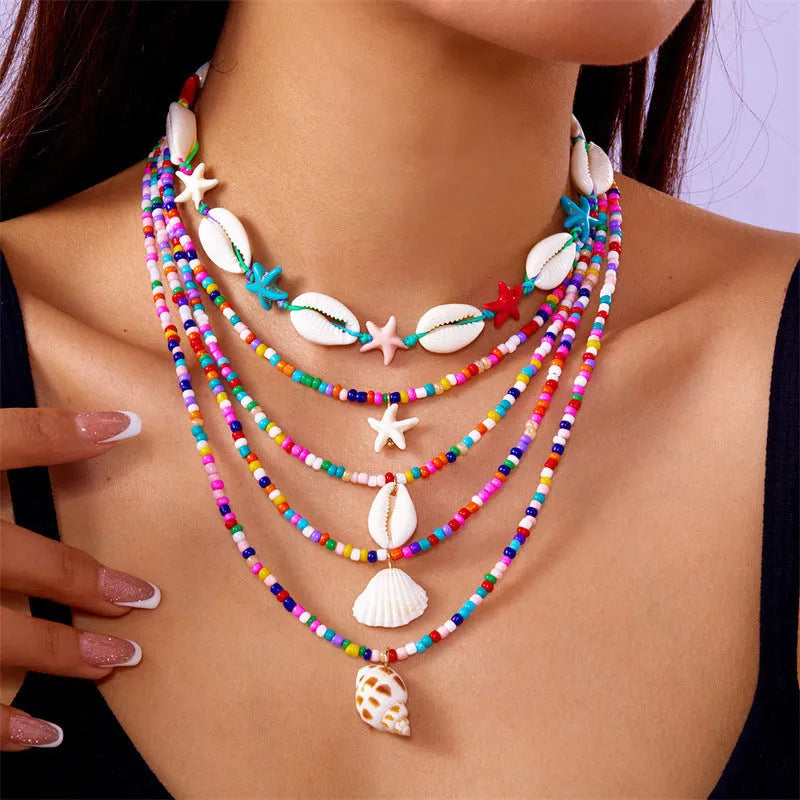 Women's five-layer shell and conch bead necklace set with adjustable chain on blue background