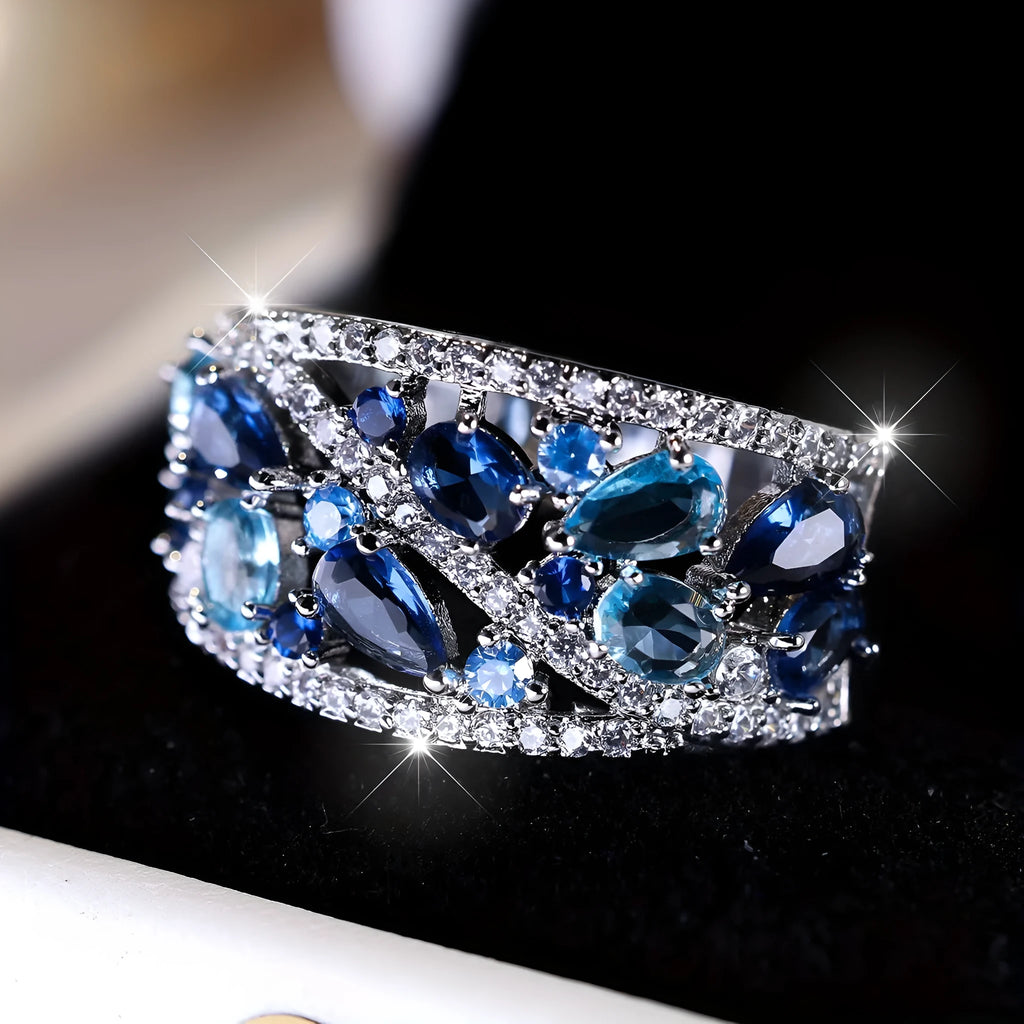 Women's hollow round fashion ring in gold or platinum finish with blue or white accents on a copper band.