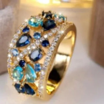 Women's hollow round fashion ring in gold or platinum finish with blue or white accents on a copper band.