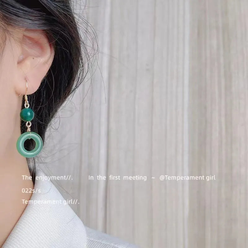 A pair of green and gold geometric earrings with a Chinese peace buckle and ring design.