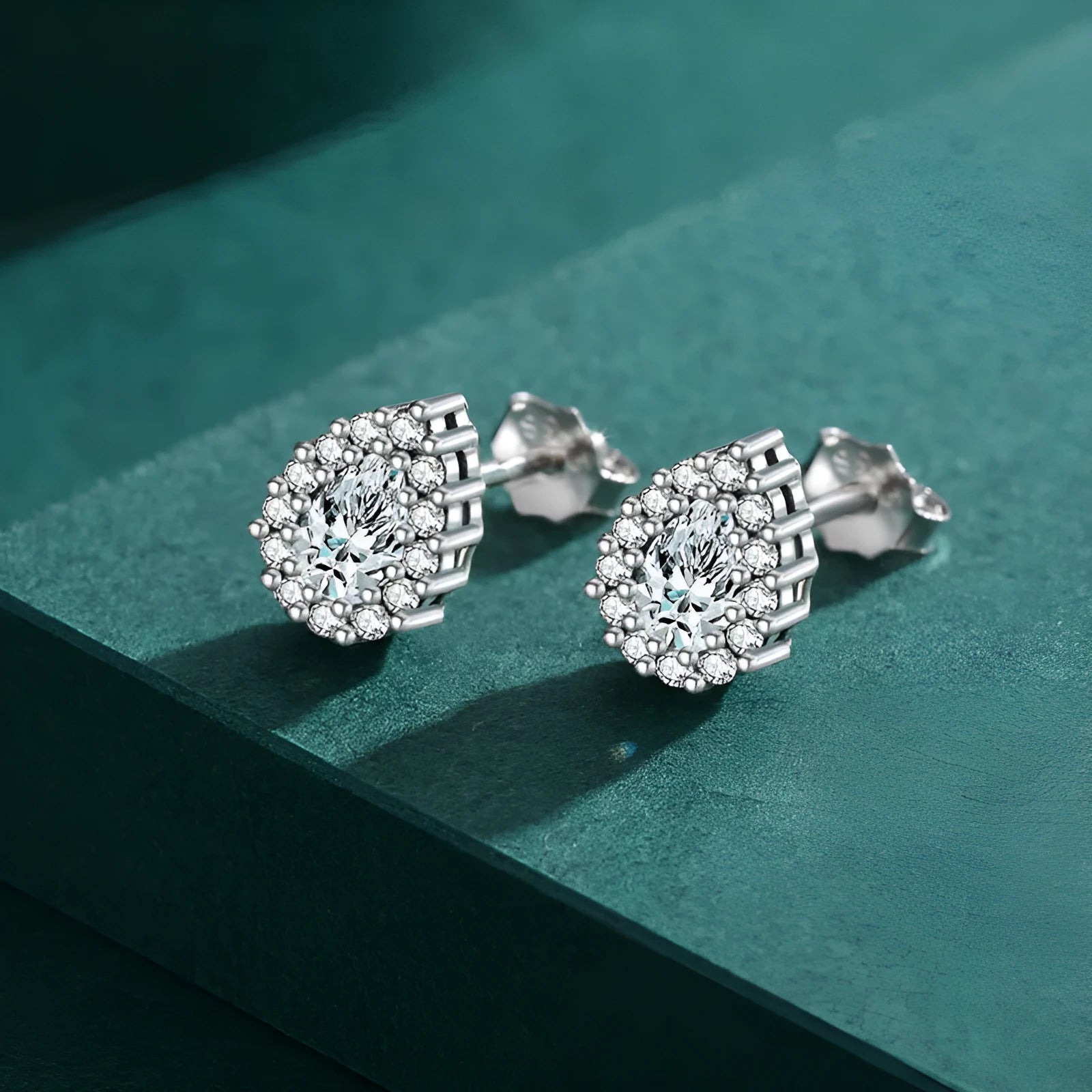 A pair of women's sterling silver water drop shaped stud earrings with a diamond-cut finish.
