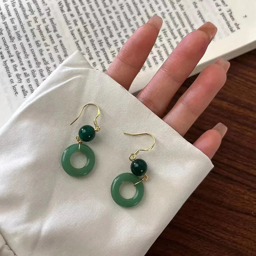 A pair of green and gold geometric earrings with a Chinese peace buckle and ring design.