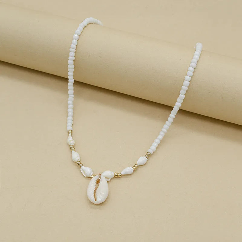 Close-up of a white conch shell bead necklace for women, showing the mother pearl shellfish pendant on a regular chain.