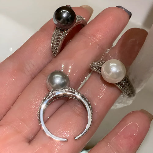 Adjustable open geometric copper ring with a black pearl for women on an index finger.