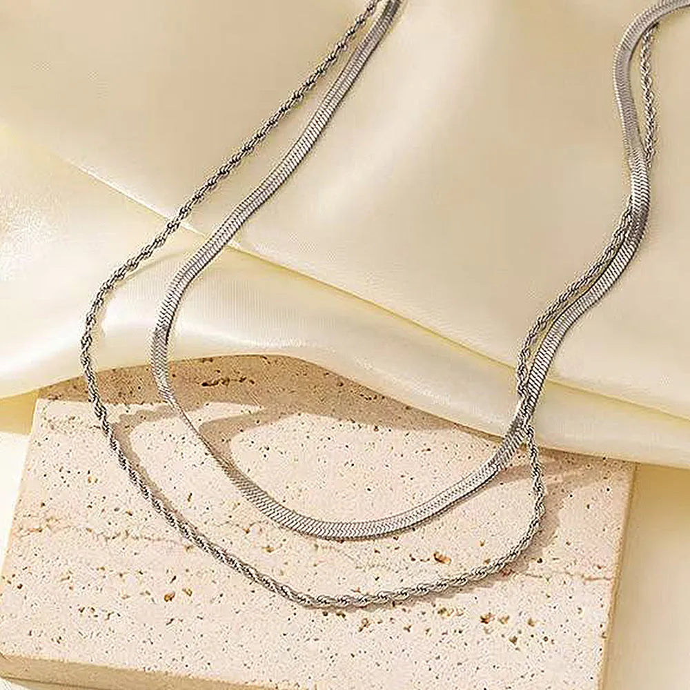Geometric double-layer twist pendant necklace on an adjustable snake bones chain in a solid colour.