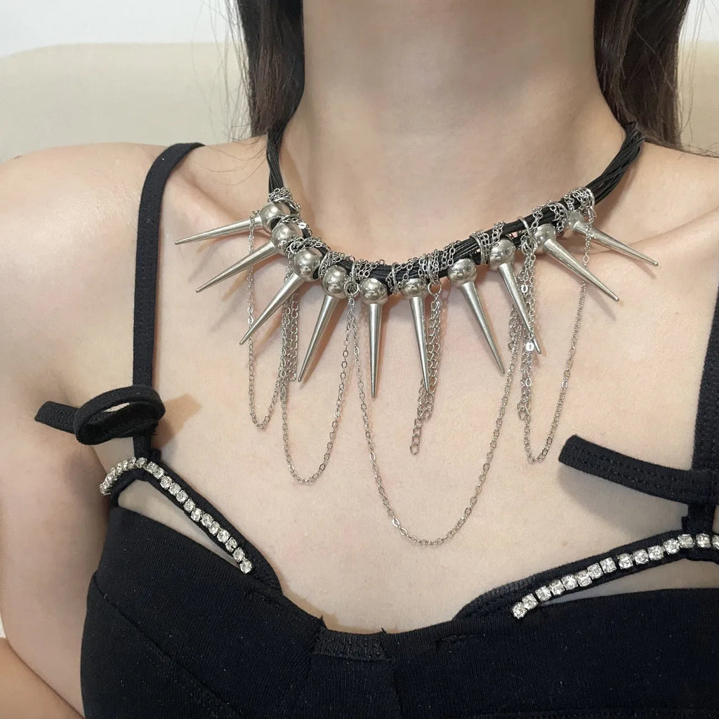 Close-up of a leather necklace with round beads, a winding tassel, and silver rivet details on a dark background.