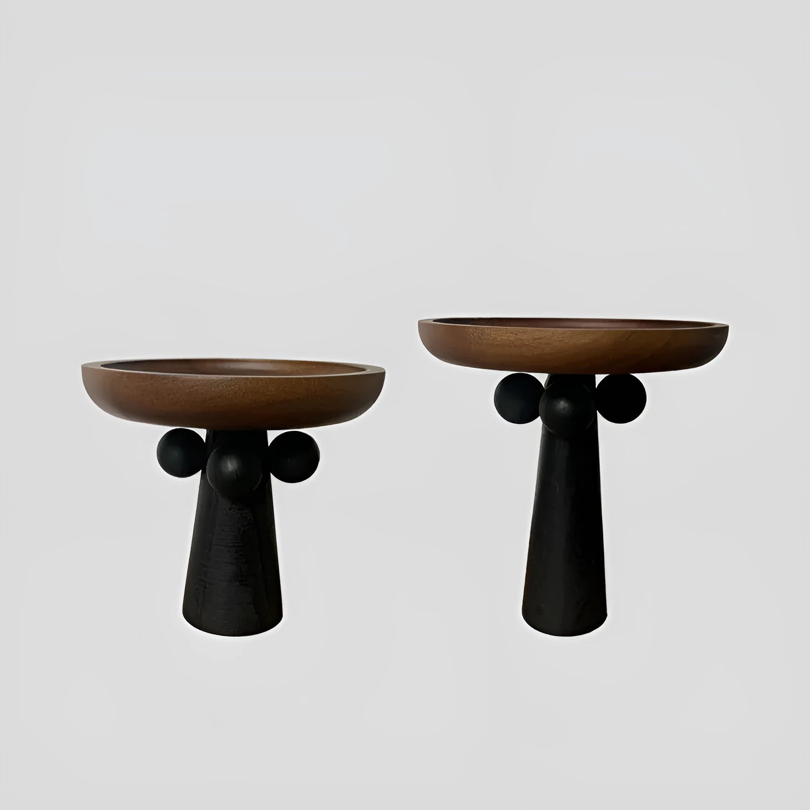Round wooden tray with high Nordic-style legs in a light wood finish holding a candle