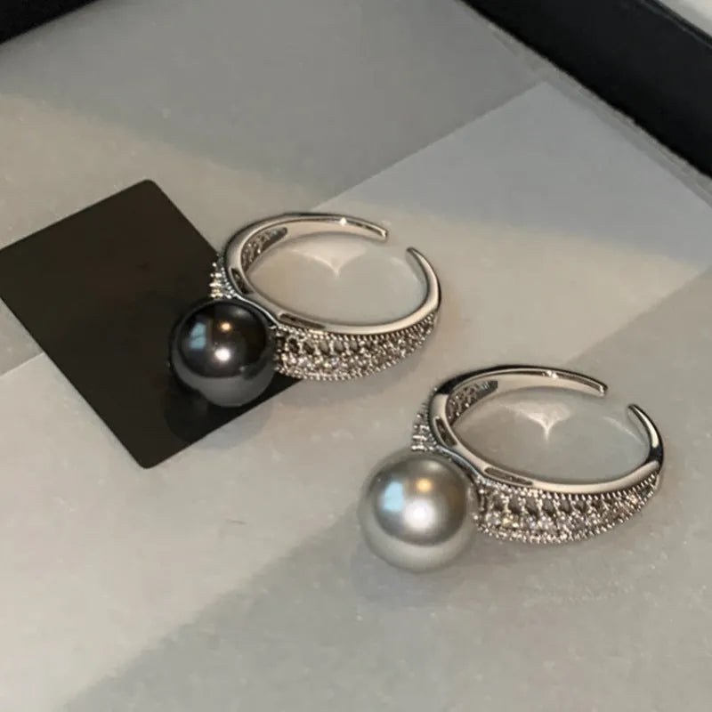 Adjustable open geometric copper ring with a black pearl for women on an index finger.