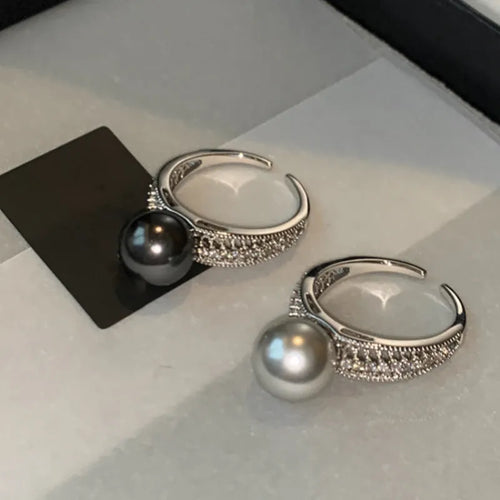 Adjustable open geometric copper ring with a black pearl for women on an index finger.