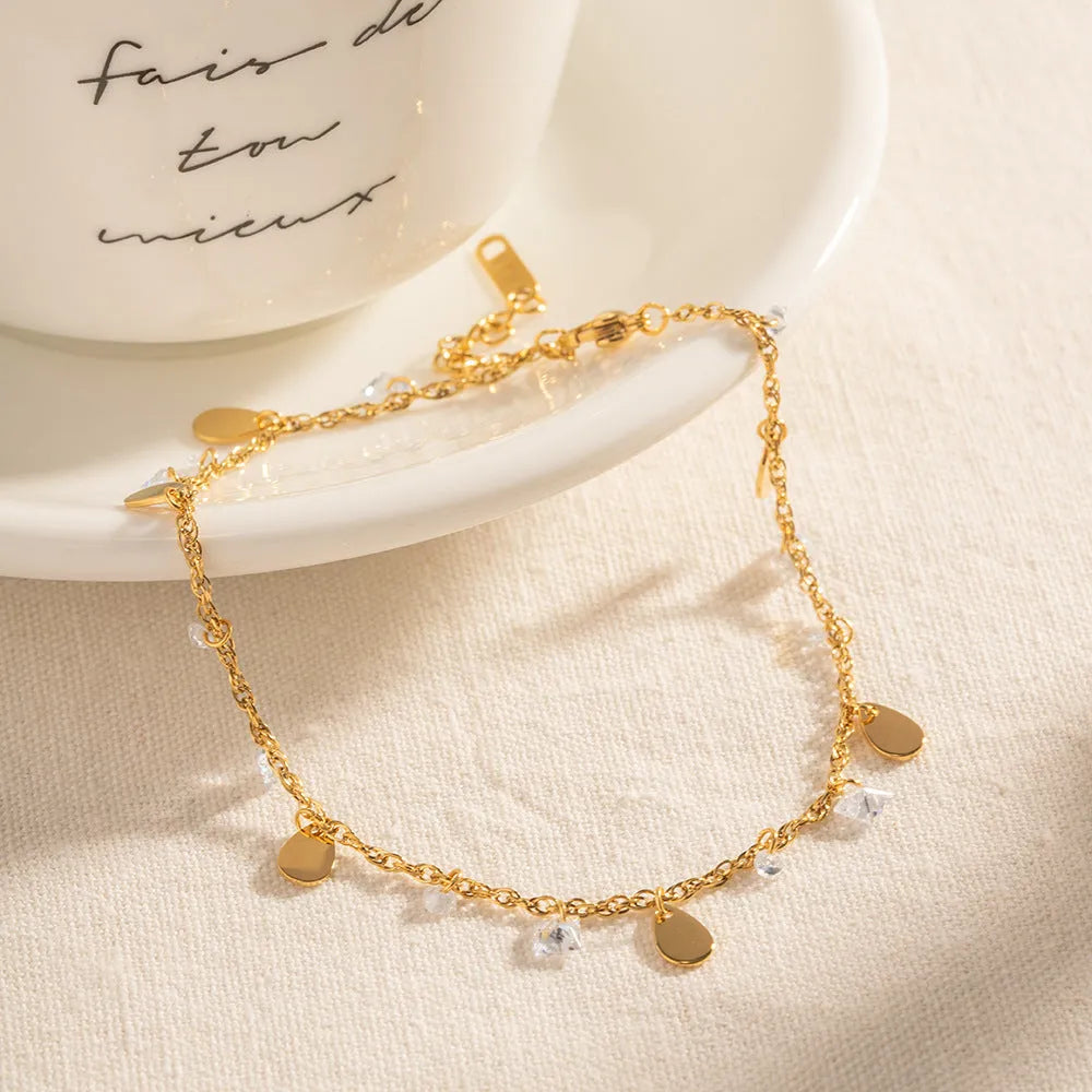 Silver stainless steel women's anklet with geometric and water drop tassel charms.