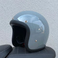 Retro-style half helmet for motorcycles with a fibreglass shell shown in a cement grey colour.