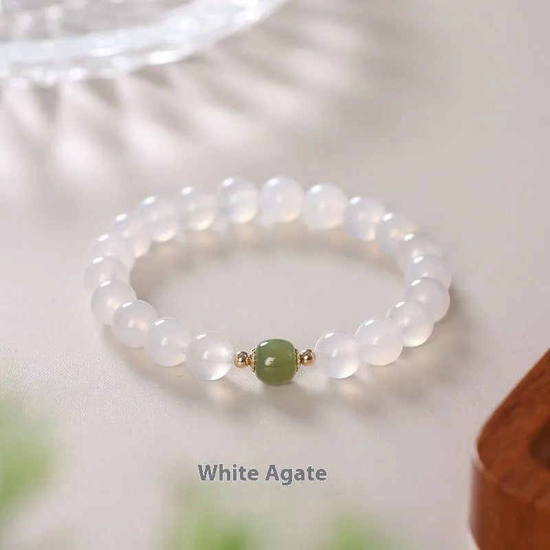 Handmade white agate and crystal bracelet with red cinnabar inlay on a wrist.