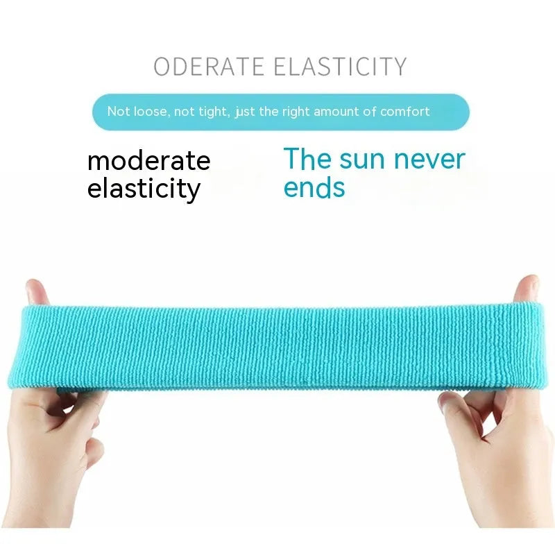 Elastic solid colour sports sweat band in black, shown on a forehead.
