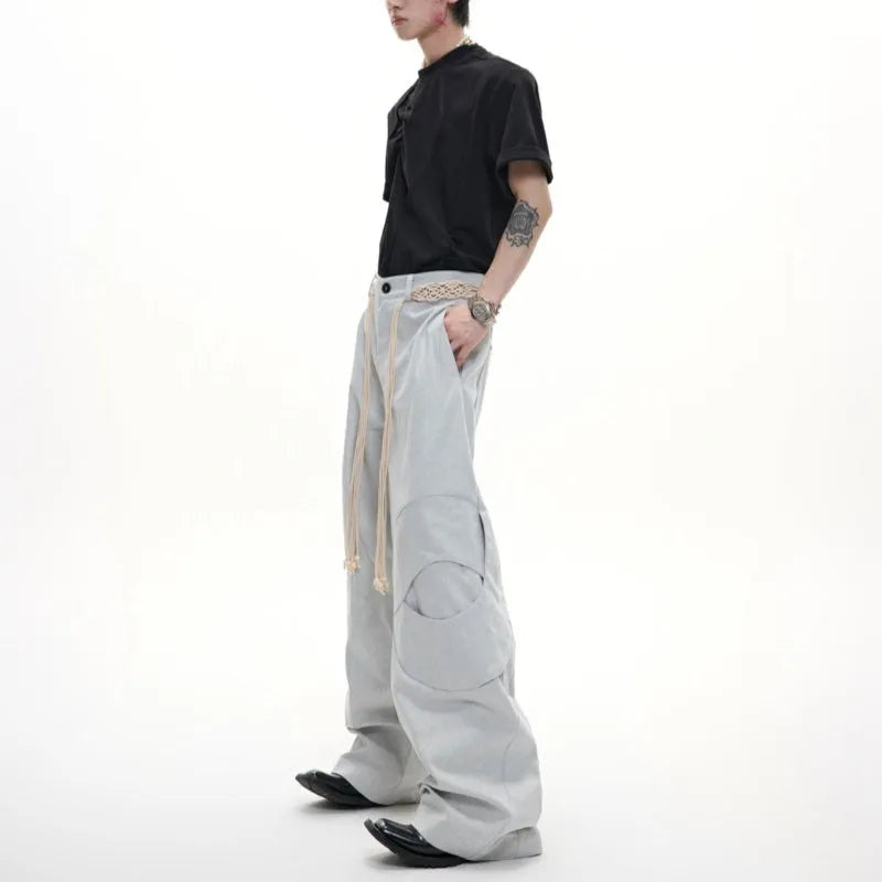 Men's dark blue straight-leg trousers showing heavy 3D cutting, belt stitching, and a front placket zipper.